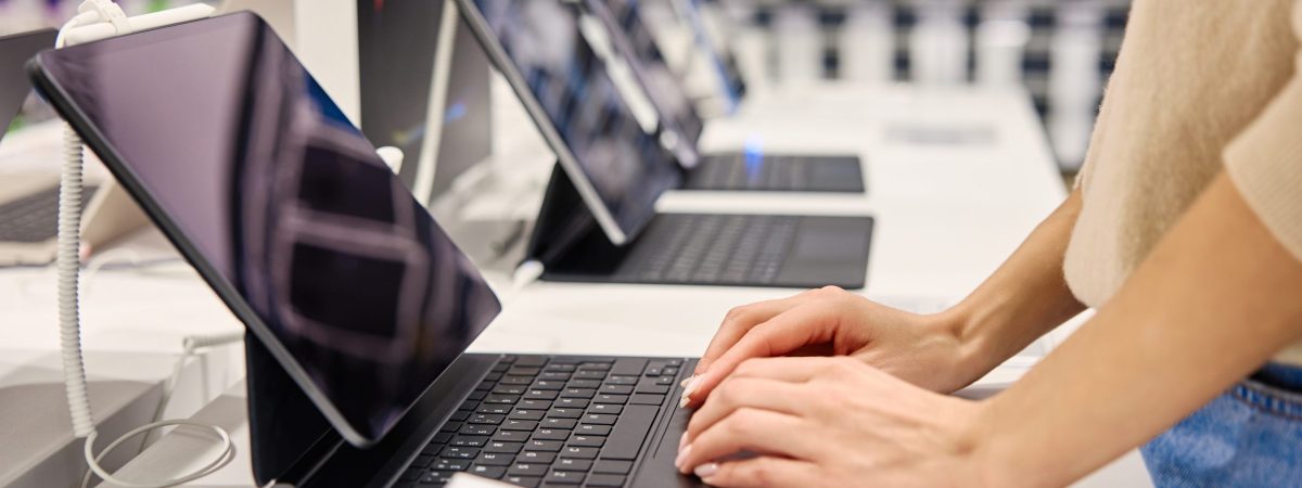 In a stylish, contemporary retail shop, a young woman is deeply engaging with various electronic devices, making this scene perfect for imagery that showcases tech retail and modern lifestyle